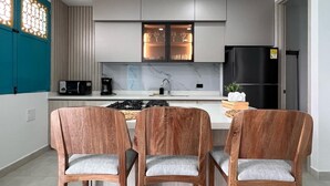 Een moderne keuken met een centraal eiland, houten stoelen en een ingebouwde magnetron.