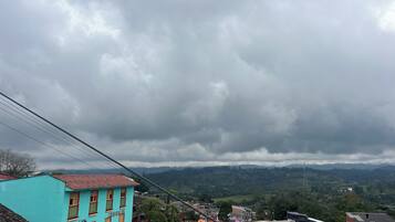 A residential area with colorful buildings, a hilly landscape, and a cloudy sky.
