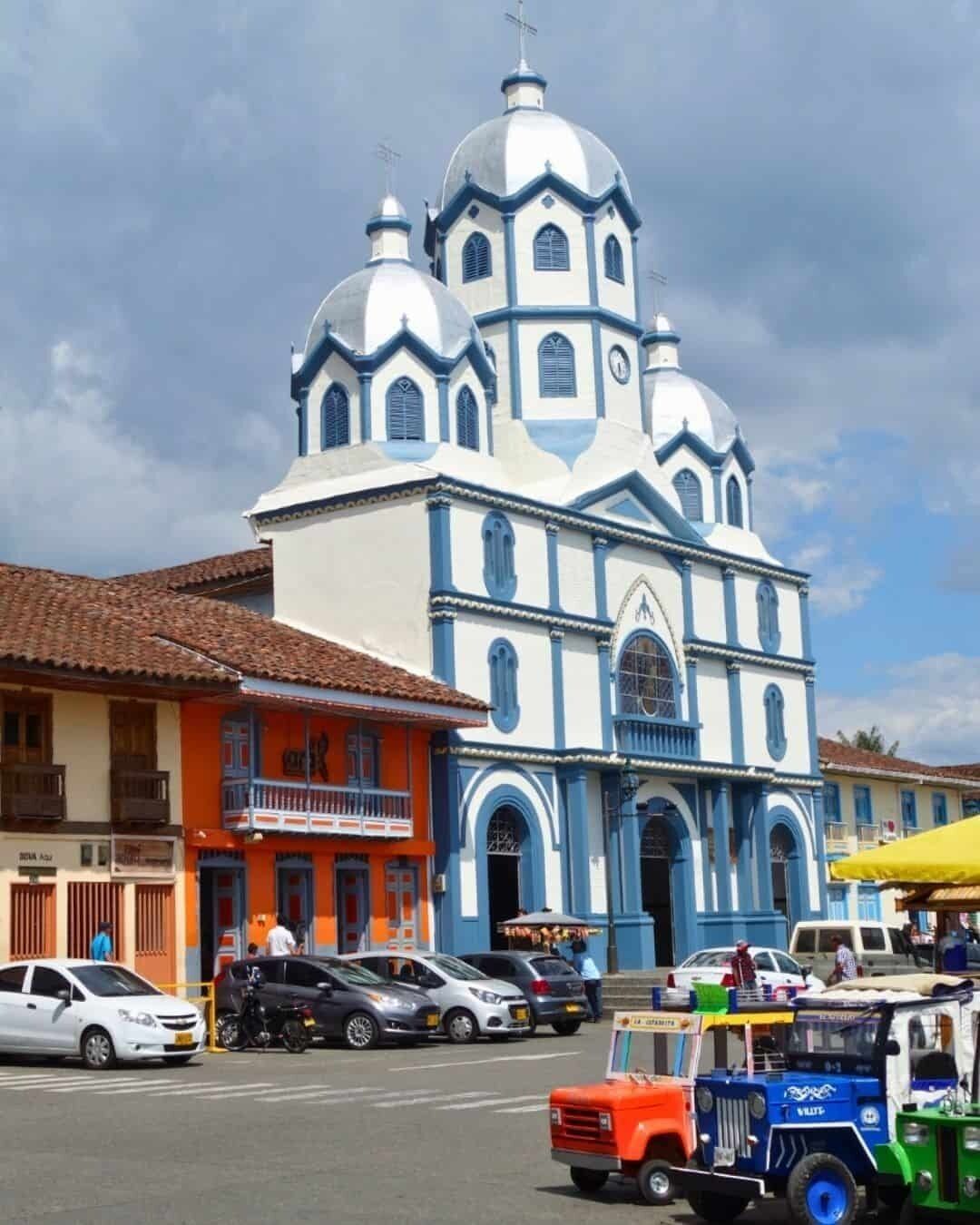 A church with a large central dome and smaller domes, surrounded by colorful buildings.
