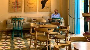 Een café interieur met houten meubels, een hanglamp en borden aan de muur.