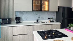 Een moderne keuken met een ingebouwde magnetron, koffiezetapparaat, spoelbak en kookplaat.