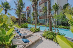 A poolside area with lounge chairs and palm trees. - Cozy 2br Apartment Pool View- canvas- bangtao area (Choeng Thale)