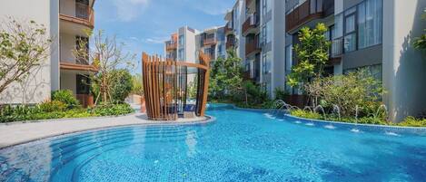Una piscina con diseño circular, rodeada de edificios modernos con balcones.