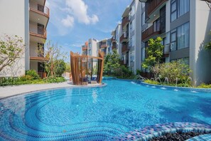 A swimming pool with a circular design, surrounded by modern buildings with balconies. - Cozy 2br Apartment Pool View- canvas- bangtao area (Choeng Thale)