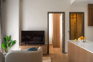 A modern living room with a flat-screen TV, a sofa, and a plant. - Cozy 2br Apartment Pool View- canvas- bangtao area (Choeng Thale)