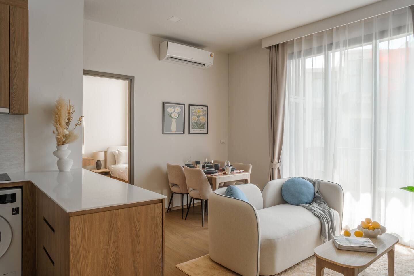 Una sala de estar moderna con sofá, mesa de comedor y zona de cocina con encimera y armarios.