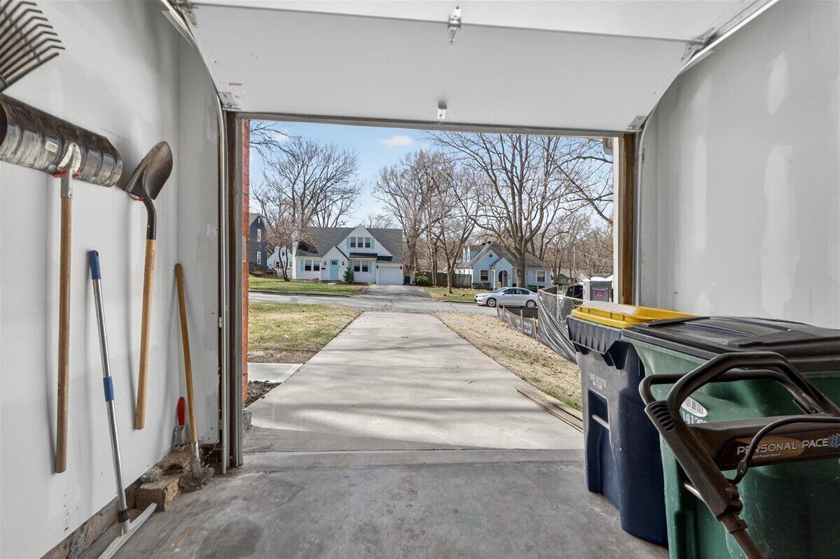Eine Garage mit Werkzeugen an der Wand, ein Auto im Hintergrund und ein grüner Müllbehälter mit der Aufschrift 'PERSONAL PACE'.