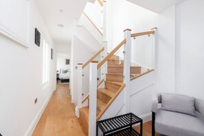 Una escalera moderna con escalones de madera y barandillas de vidrio, que conduce a un segundo piso.