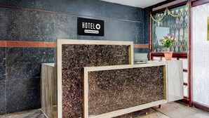 A hotel reception desk with a sign that reads 'HOTELO Company-Serviced.' - Deluxeannakilly Tower Guest House (Chennai)