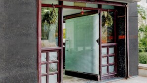 A building entrance with a glass door and a tiled wall. - Deluxeannakilly Tower Guest House (Chennai)