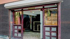 A building entrance with a staircase leading inside, a tiled floor, and a window with hanging plants. - Deluxeannakilly Tower Guest House (Chennai)
