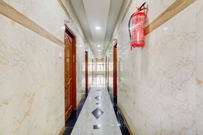 A marble-floored corridor with doors numbered 105 and 106, and a fire extinguisher mounted on the wall. - Townhouse Koyambedu Metro Station (Chennai)