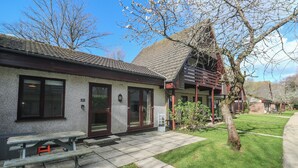A building with a tiled roof, a wooden bench, and a grassy lawn. - Tolroy Manor Holiday Park (Hayle)