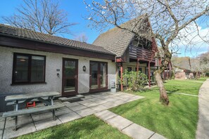 A building with a tiled roof, a wooden bench, and a grassy lawn. - Tolroy Manor Holiday Park (Hayle)