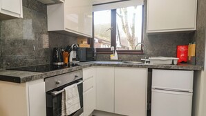 A compact kitchen with a built-in oven, a microwave, and a refrigerator. - Tolroy Manor Holiday Park (Hayle)