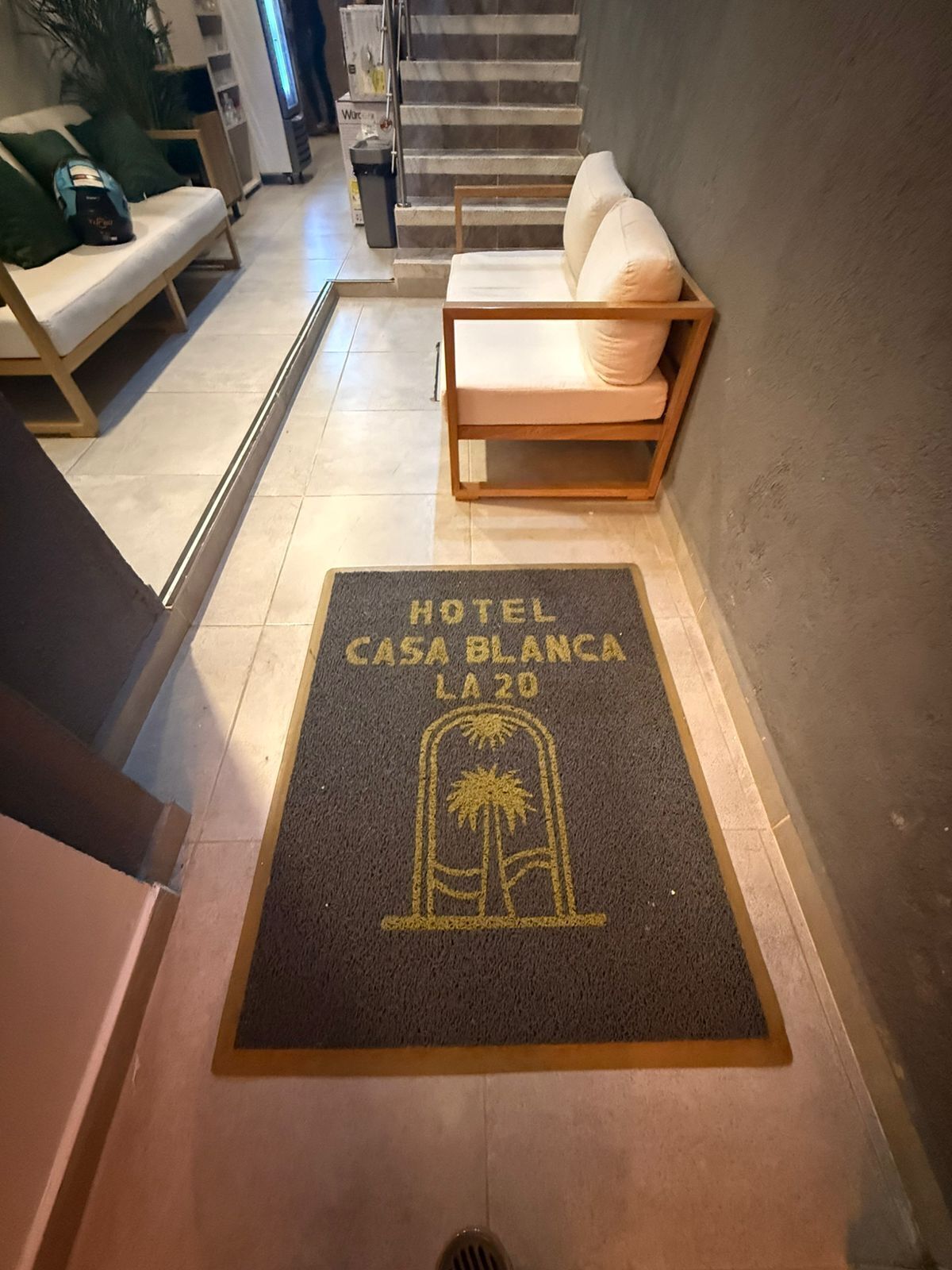Entrada de un hotel con un felpudo que dice 'HOTEL CASA BLANCA LA 20' y un diseño de palmera.