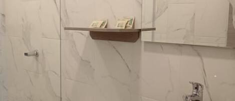 A bathroom with a marble wall, a toilet, a sink, and a shower.
