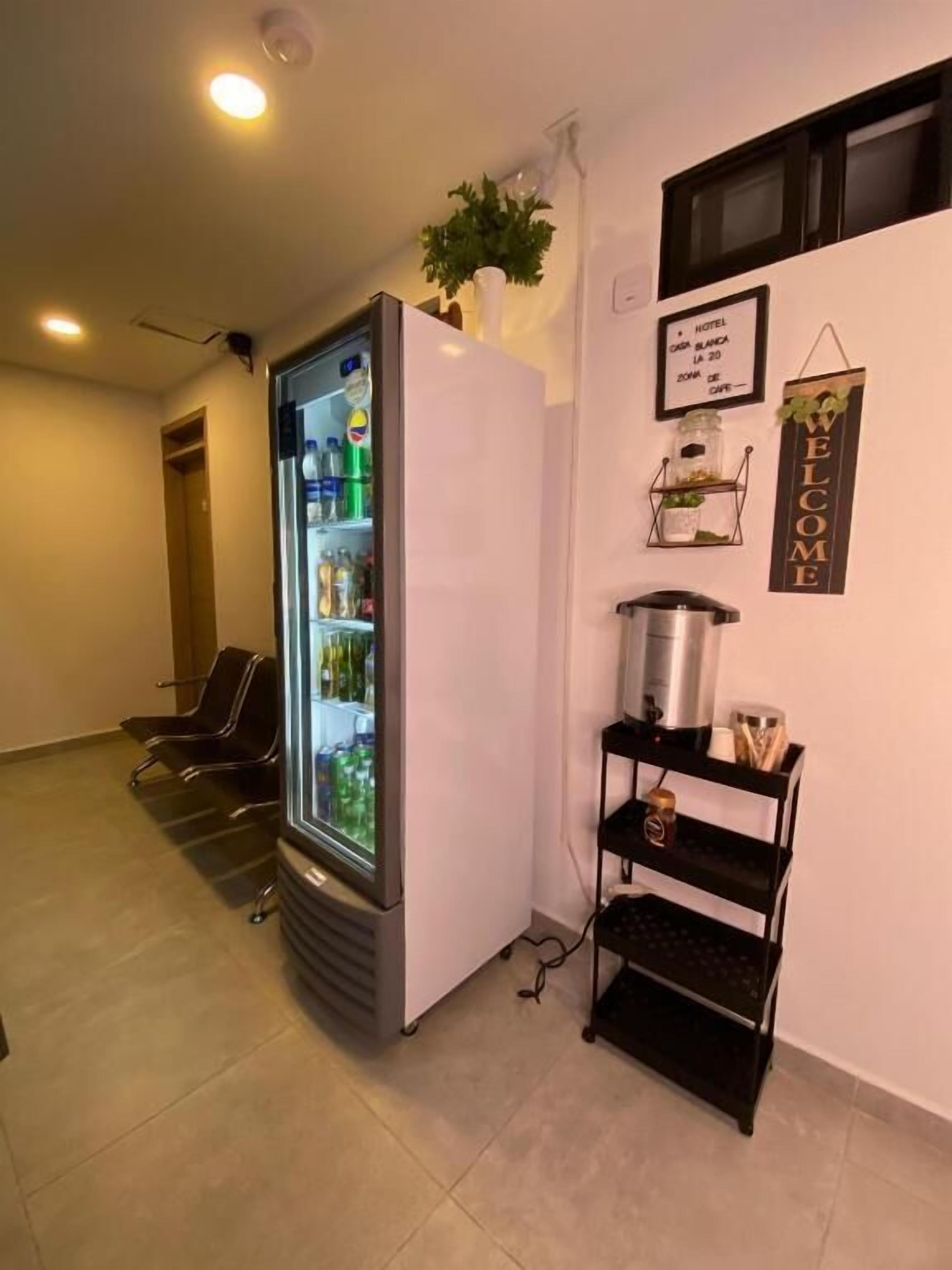 A hotel room with a minibar, a wall-mounted sign, and a small shelf with items.