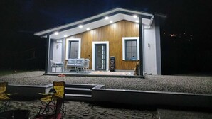 Une maison moderne avec une façade en bois, deux fenêtres et un balcon doté d’un espace salon extérieur.