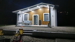 Une maison moderne avec une façade en bois, un balcon doté d’un espace salon et un petit jardin.