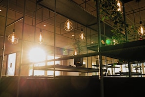 A modern interior with hanging light fixtures, a metal ceiling grid, and a potted plant. - Comfortably furnished vacation apartment with fallow deer enclosure and restaurant. (Erwitte)