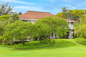 A two-story building with a red-tiled roof, surrounded by lush greenery and a well-maintained lawn. - Kiahuna #44 • A/C • REMODELED & UPDATED Ground-Floor End Unit • 2 Min to Beach (Koloa)
