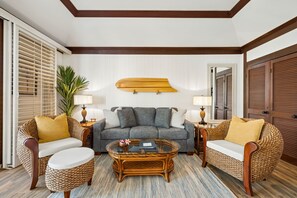 A living room with a sofa set, a coffee table, and a surfboard mounted on the wall. - Kiahuna #44 • A/C • REMODELED & UPDATED Ground-Floor End Unit • 2 Min to Beach (Koloa)