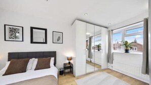 Een moderne slaapkamer met een bed, nachtkastje, lamp en kunst aan de muur.
