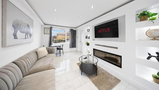 Een moderne woonkamer met een bank, een open haard, een televisie en een eethoek.