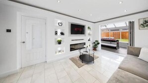 Een moderne woonkamer met een flatscreen televisie, een open haard en een bank.