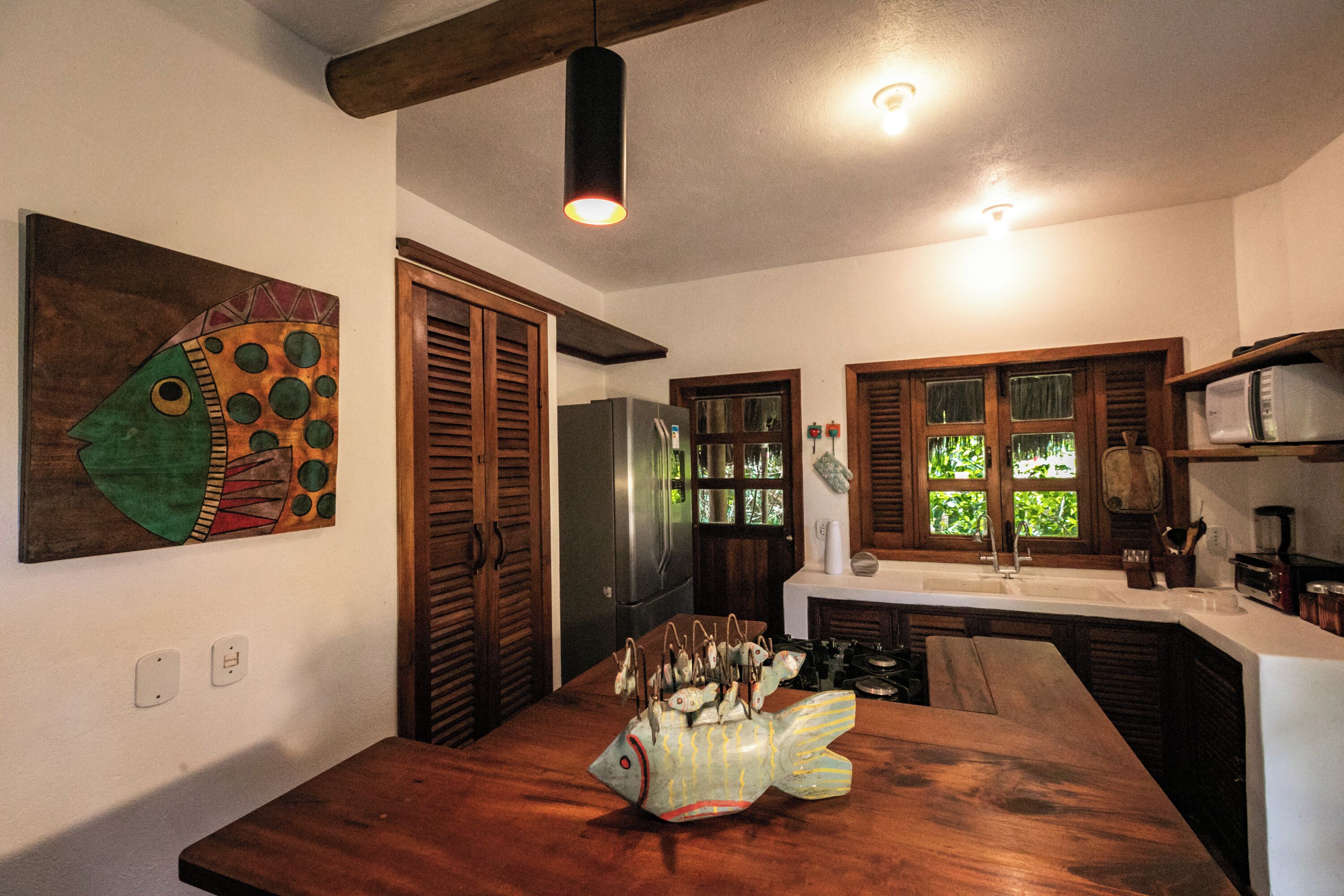 A kitchen with wooden cabinets, a stainless steel refrigerator, and a fish-shaped centerpiece on the counter.
