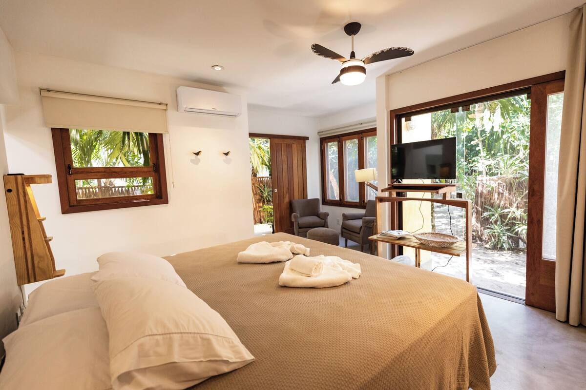 Una camera d'albergo con un letto, una televisione, una ventola a soffitto e vista sull'esterno.