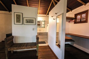 Una habitación con un banco de madera, un espejo y obras de arte enmarcadas en la pared.