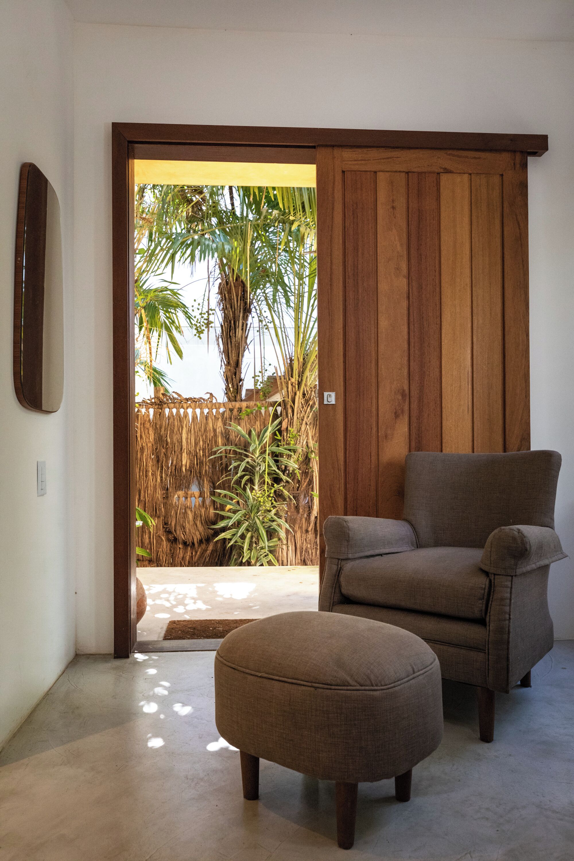 A room with a sliding door leading to a patio, a sofa, and an ottoman.