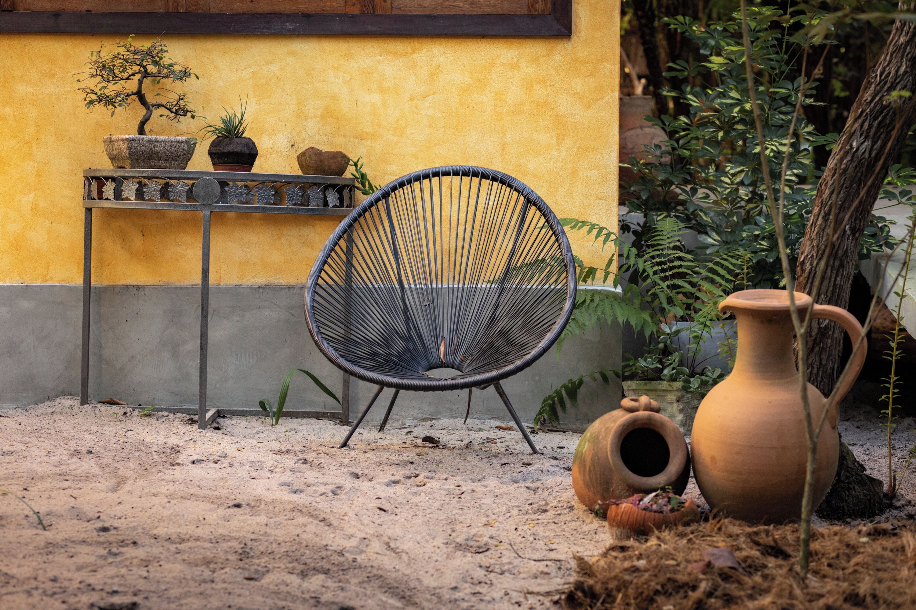 A chair, potted plants, and a large vase in an outdoor setting.