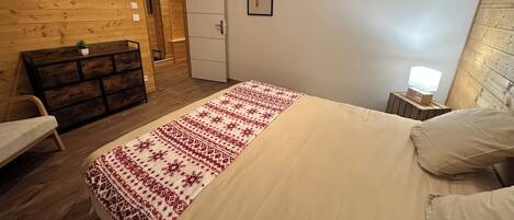 Makuuhuoneessa on sänky, lipasto, tuoli, vaatekaappi ja yöpöytä, jossa on lamppu.