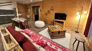 Una sala de estar acogedora con sofá, mesa de centro, televisión y área de cocina.