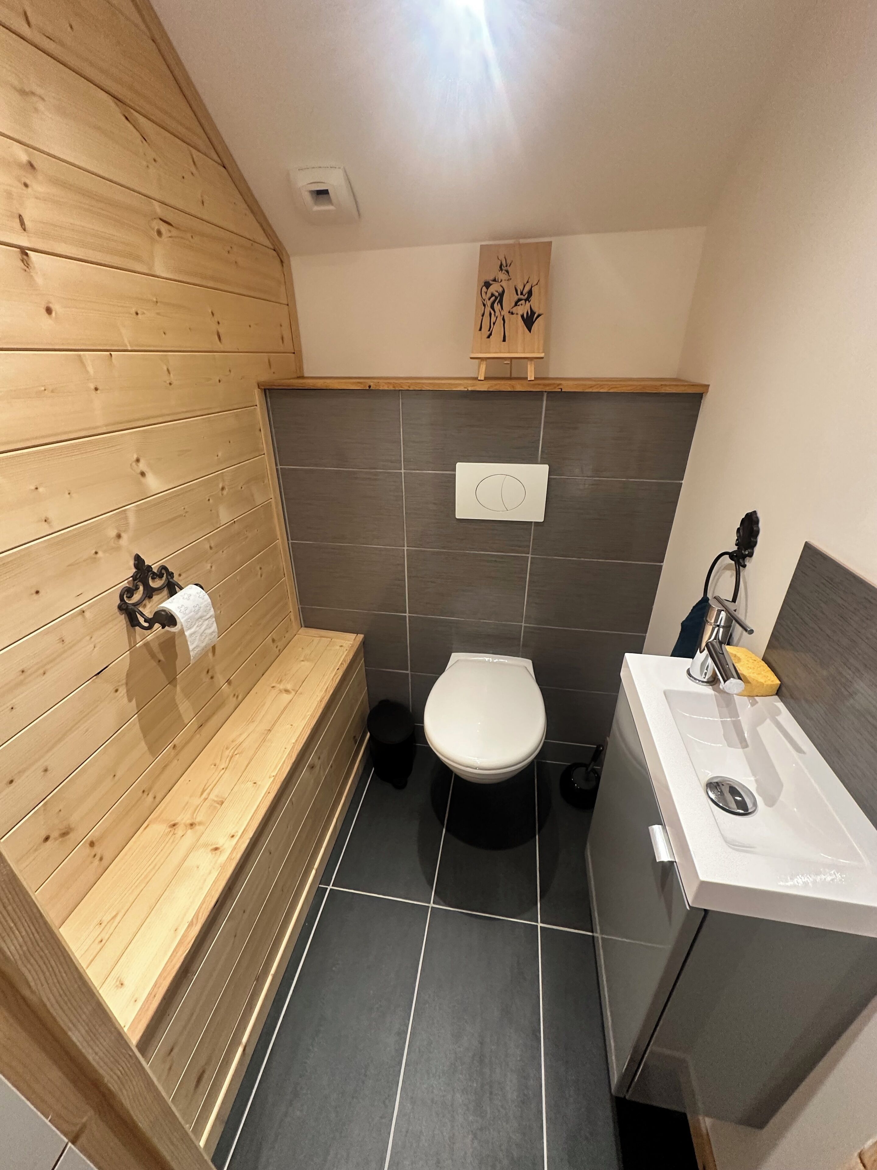 A bathroom with a wooden bench, a toilet, and a sink.