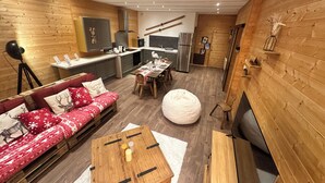 Un interior moderno con temática de madera, que incluye un sofá, una mesa de comedor y una zona de cocina.