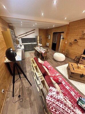 A modern interior with a dining area, kitchen, and a cozy seating area with a bean bag and a small table. - L'Appart'Chalet du Revermont - for 4 people - (Cousance)