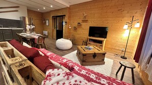 Una sala de estar acogedora con sofá, mesa de centro de madera y televisor.