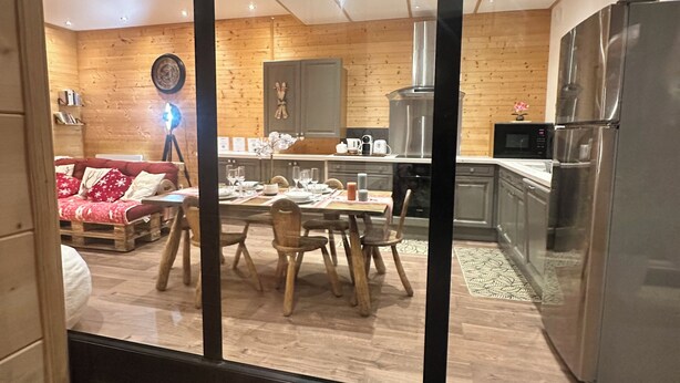Una cocina moderna con paneles de madera, electrodomésticos de acero inoxidable y un comedor con mobiliario de madera.