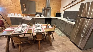 Una cocina moderna con muebles de madera, un refrigerador de acero inoxidable y una mesa de comedor preparada para cuatro personas.