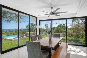 A dining area with a view of a swimming pool and greenery. - Sun Bliss | Stunning Infinity Pool & Ocean Views (Aguada)