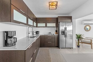 A modern kitchen with a stainless steel refrigerator, a coffee machine, and a sink. - Sun Bliss | Stunning Infinity Pool & Ocean Views (Aguada)