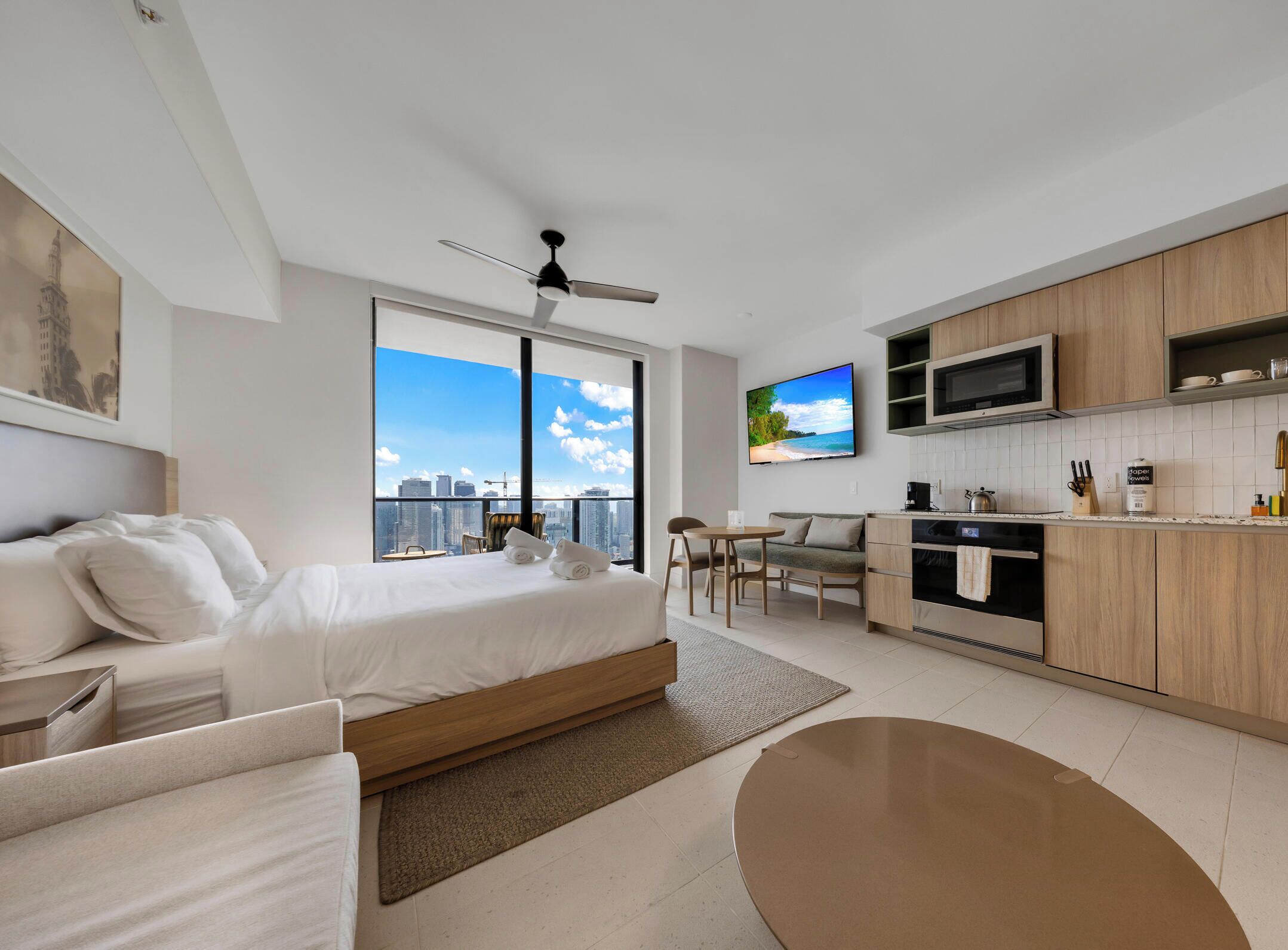 Une chambre d’hôtel moderne équipée d’un lit, d’un canapé, d’un coin repas, d’une cuisine et d’un téléviseur.