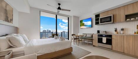Une chambre d’hôtel moderne équipée d’un lit, d’un canapé, d’un coin repas, d’une cuisine et d’un téléviseur.