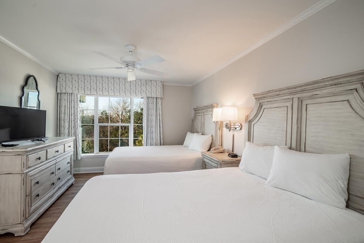 Recharge in a sunlit bedroom with plush linens and space.
