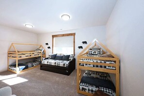 A room with two bunk beds, a window, a mirror, and a ceiling light.