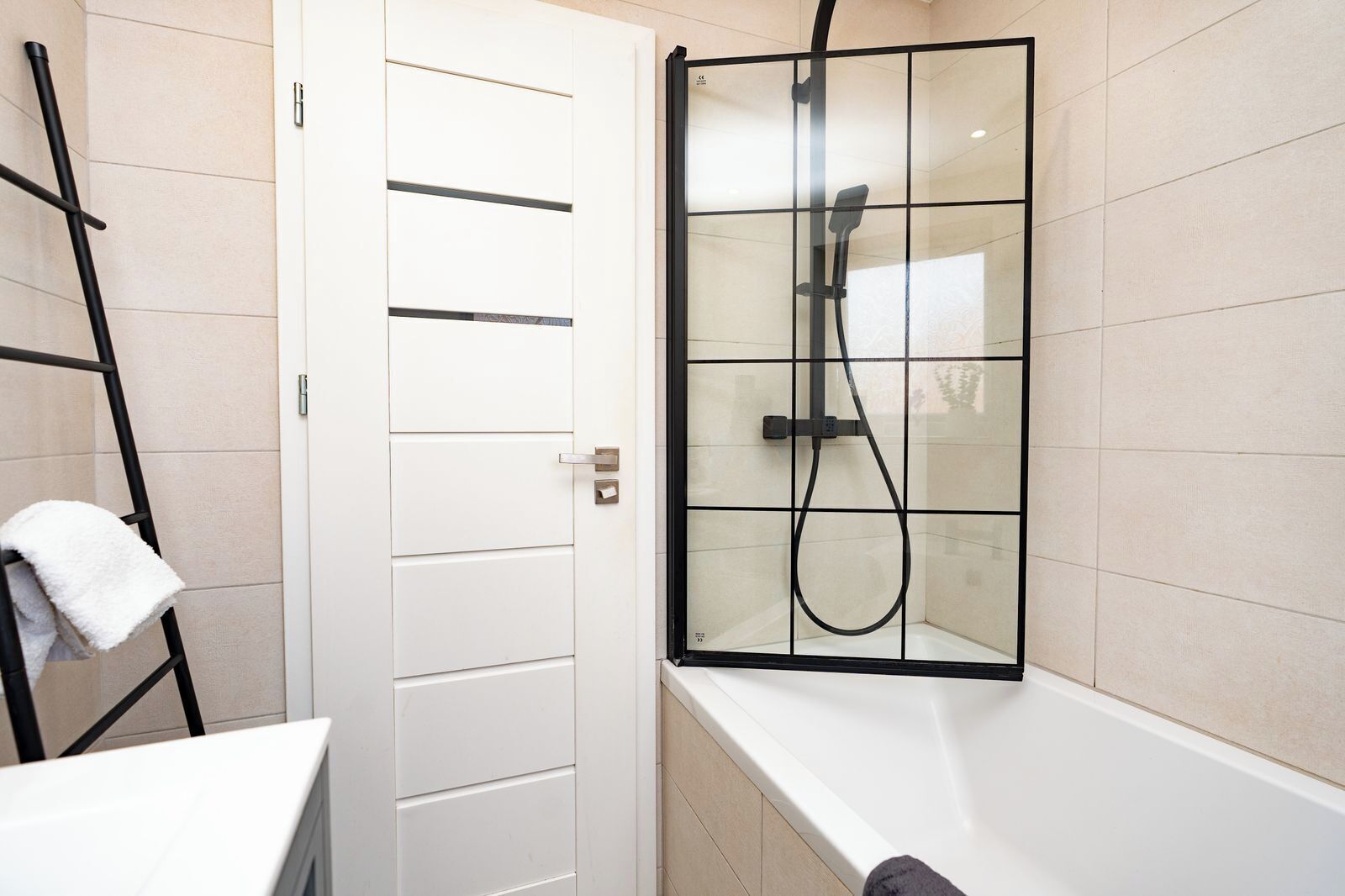 Ein Badezimmer mit Duschkabine, Handtuchhalter und einer weißen Tür.